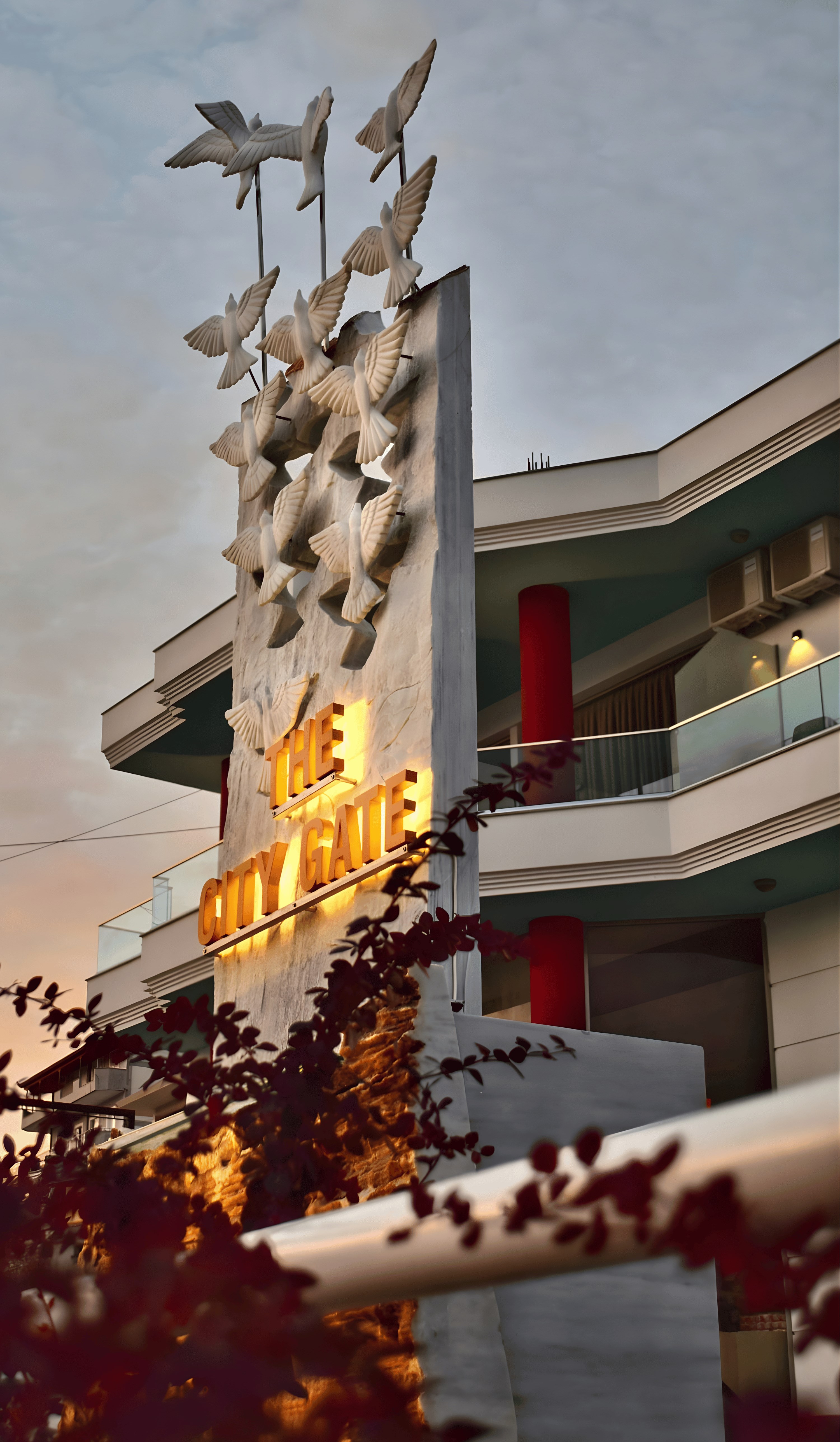 The City Gate Hotel entrance and bird sculpture at sunset